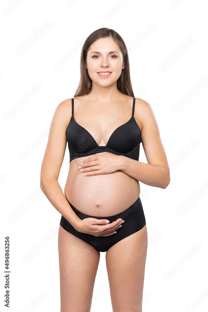 Young pregnant woman in black swimsuit. Girl expecting a baby and touching her belly isolated on white background. Young pregnant woman in black swimsuit. Girl expecting a baby and touching her belly isolated on white background.