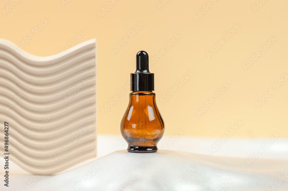 Natural hyaluronic serum in a bottle with a pipette. Natural essential oil or serum in a bottle with a pipette on a gray podium.