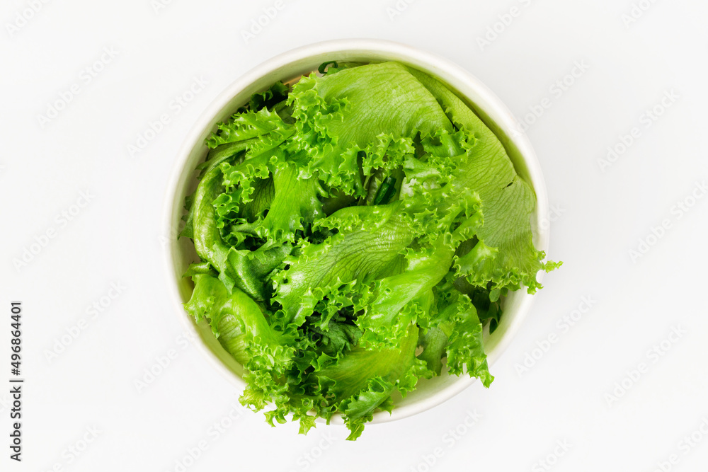 A bowl of frillis lettuce leaves on  a white background. Top view. - obrazy, fototapety, plakaty 