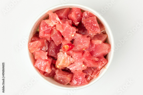 A bowl of sliced tuna in soy sauce on a white background. Top view.