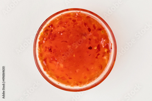 A cup with sweet chili sauce. White background. Top view.
