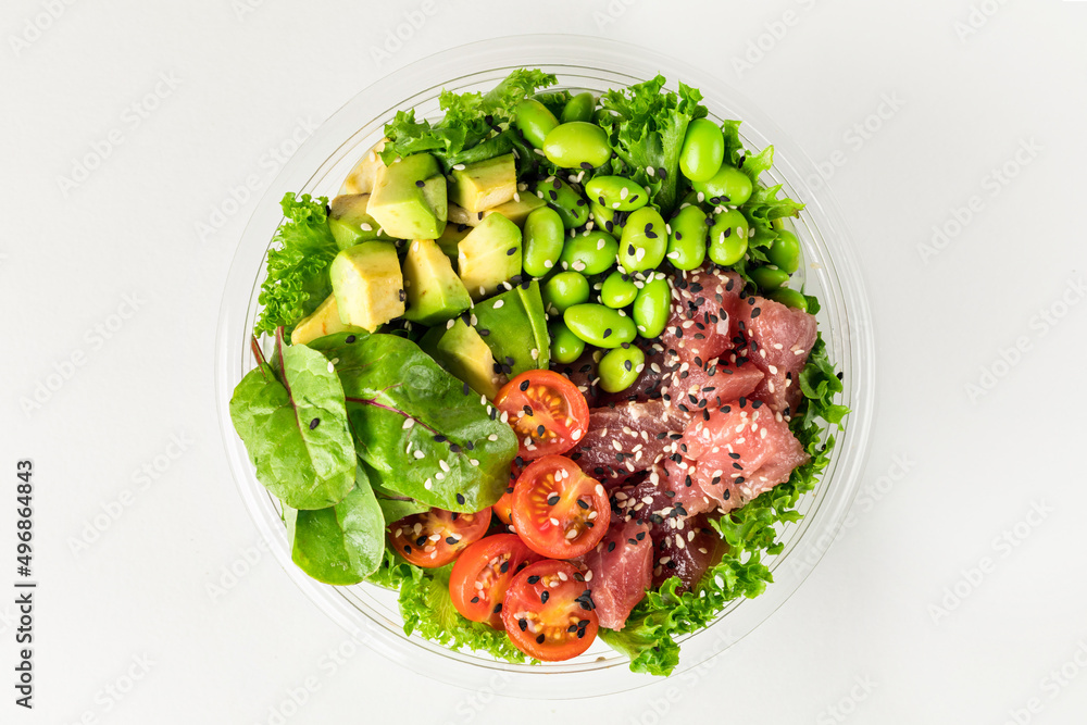 Poke bowl with tuna, salad leafs, edamame beans, avocado, cherry tomatoes and spinach on awhite background. Plastic tableware for delivery. Top view. Poke bowl with tuna, salad leafs, edamame beans, avocado, cherry tomatoes and spinach on awhite background. Plastic tableware for delivery. Top view.