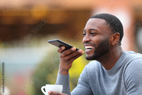Fotografiet Happy man with black skin dictating message on phone