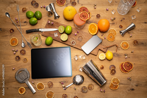Online cocktail course with blank tablet, smartphone and bartender tools on wood kitchen table photo