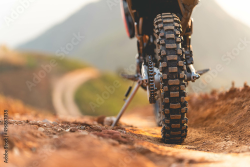 Part of a motocross wheel on a mound, with sunrise copyspace for your individual text. A part of a dirt road dirt bike in the forest 