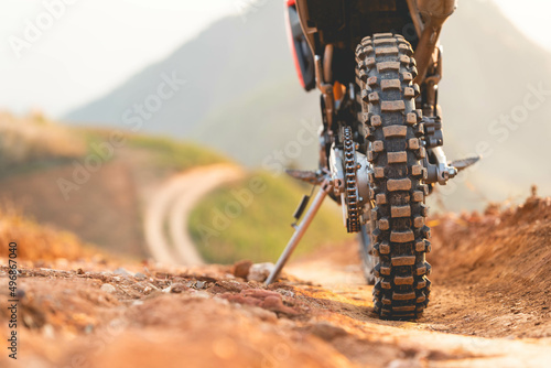 Part of a motocross wheel on a mound, with sunrise.beautiful mountain scenery backdrop adventure concept. copyspace for your individual text