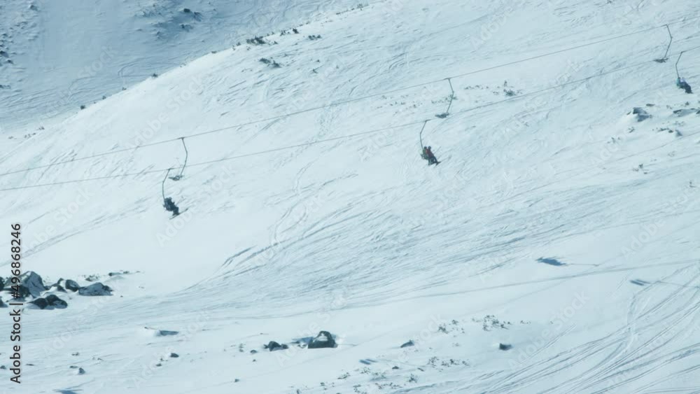 Chairlifts of alpine ski resort transport skiers along snowy slope Chairlifts of alpine ski resort transport skiers along snowy slope