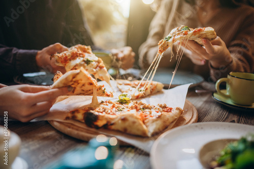 Three firends together eating pizza in a cafe