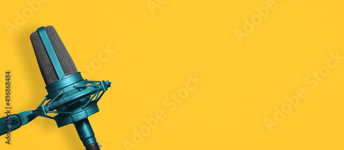 Blue vocal microphone on yellow background banner with copy space for podcast or newscast photo