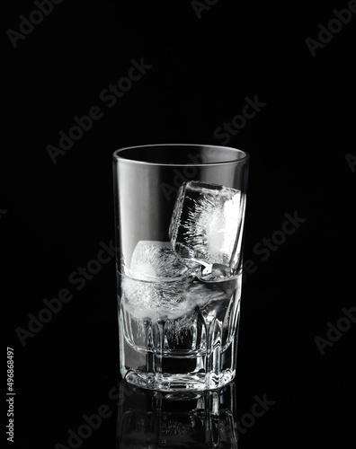 Glass with ice and water on black background