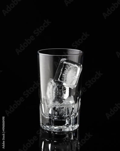 Ice cubes in empty glass on black background. Glass of water or whiskey and wine. Empty glass for alcoholic beverages