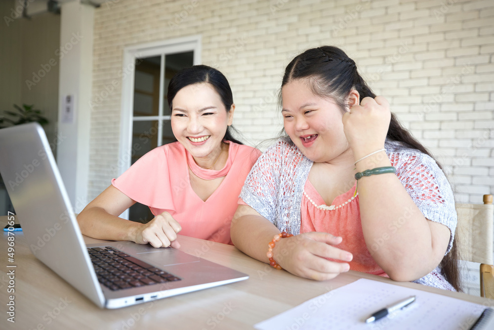 down syndrome teenage girl and her teacher studying how to use laptop computer for education, and raised arm pose in success down syndrome teenage girl and her teacher studying how to use laptop computer for education, and raised arm pose in success