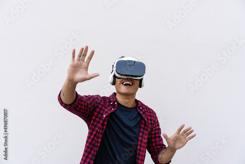 Oriental young man having fun with vr glasses against a blue sky and clouds - Social influencer playing with new trends tech opportunities - Metaverse, fictional world and virtual reality concept