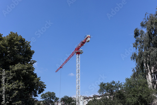 Crane against the blue sky. Red-white crane at a construction site