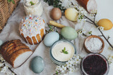 Traditional Easter basket food. Natural dyed easter eggs, stylish easter bread, ham, beets, butter, cheese on rustic wooden table with spring blossoms and linen napkin. Top view.