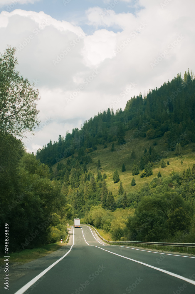 A truck transports cargo on a highway surrounded by mountains in the Carpathians