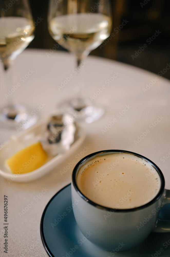 Hot latte on the table, and in the background oysters and a glass of champagne Hot latte on the table, and in the background oysters and a glass of champagne