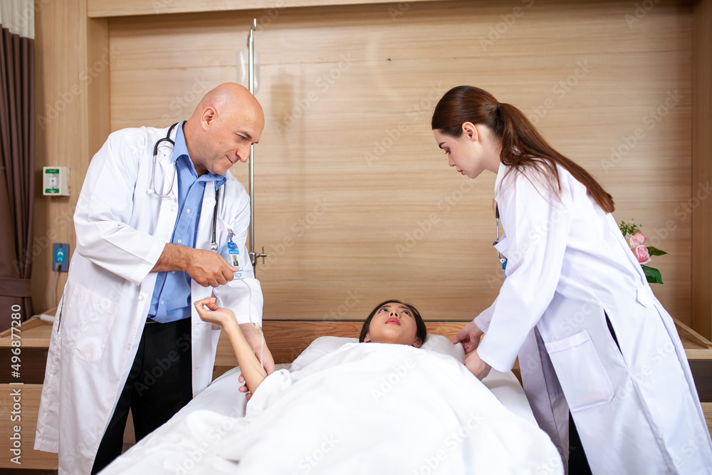 Obraz premium Group of doctor visiting ward have woman patient and check her with stethoscope on bed. Woman patient lying on hospital bed while doctor giving her checkup.
