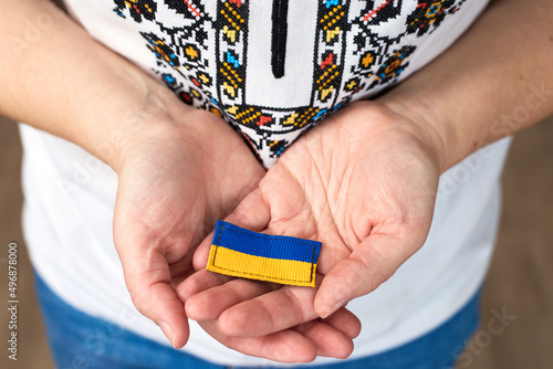 Female in traditional ukrainian clothes hold in hands ribbon with ukrainian flag photo