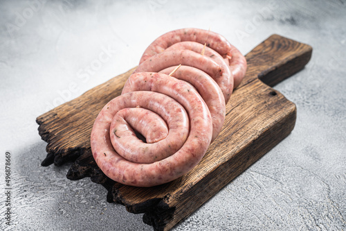 Ready for cooking Raw spiral pork meat sausages on a wooden board. White background. Top view