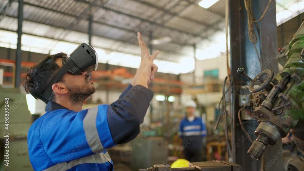 Engineer wearing virtual reality headset standing in the manufacturing factory. Moving hand and looking around the data. Working with Holographic Animations. High technology and industrial concept Engineer wearing virtual reality headset standing in the manufacturing factory. Moving hand and looking around the data. Working with Holographic Animations. High technology and industrial concept