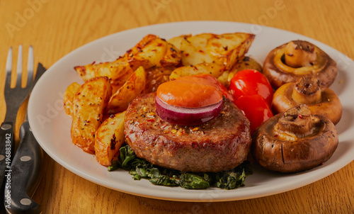 Beefburger with potato wedges, mushrooms and tomatoes.