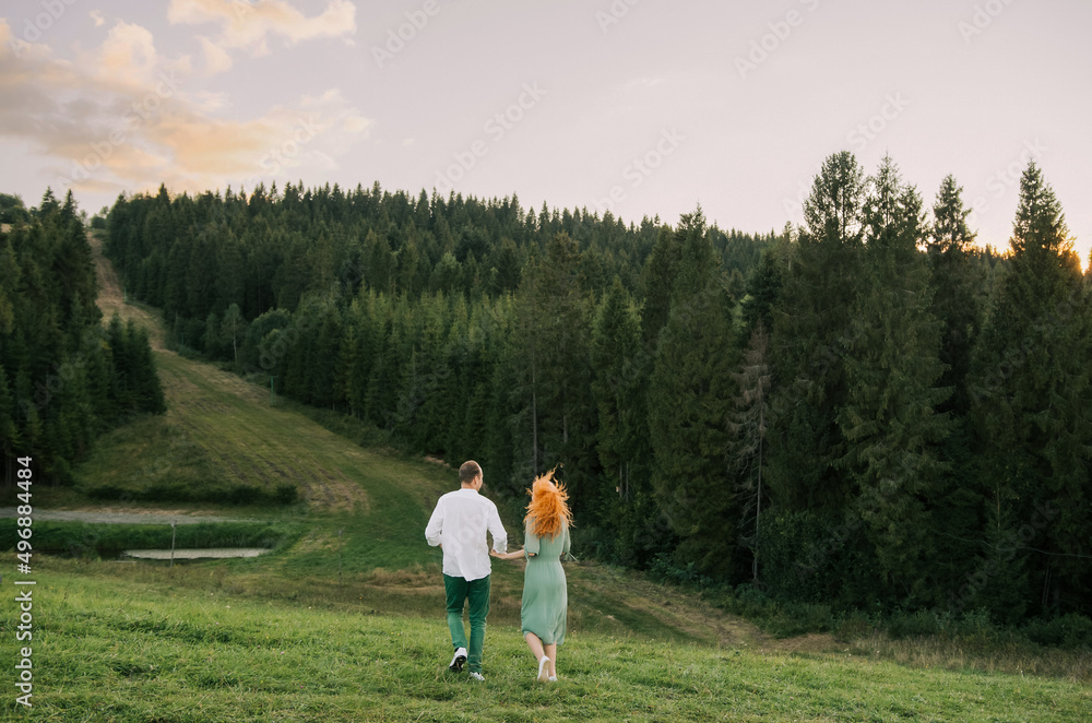 Portrait of a happy young woman holding her boyfriend's hand while walking in the mountains on vacation. Couple enjoying a hike in nature. Portrait of a happy young woman holding her boyfriend's hand while walking in the mountains on vacation. Couple enjoying a hike in nature.