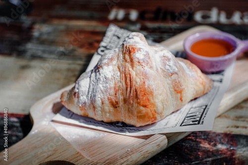 Croissant placed on paper with honey in a small cup ready to eat.