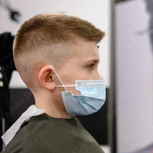 Schoolboy in a barbershop during a pandemic  stylish haircut for baby.