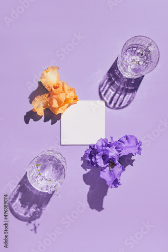 Papier peint Two glasse with water and card note with iris flowers on pastel lilac background