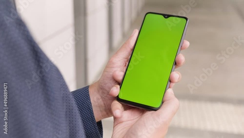 A man looks at a smartphone (vertical) with green screen - closeup