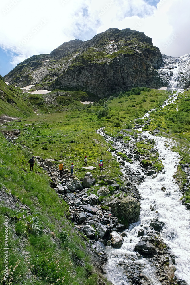 Obraz premium Summer landscape with Sofia waterfalls and group of tourists hiking on mountain plateau, natural background. trip, journey, adventure. Caucasus mountains, Karachay-Cherkess Republic. Arkhyz