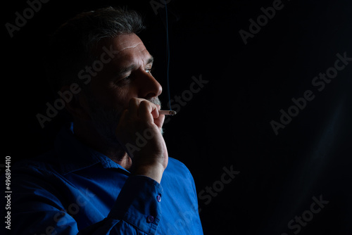A mature handsome white bearded man smokes a cigarette