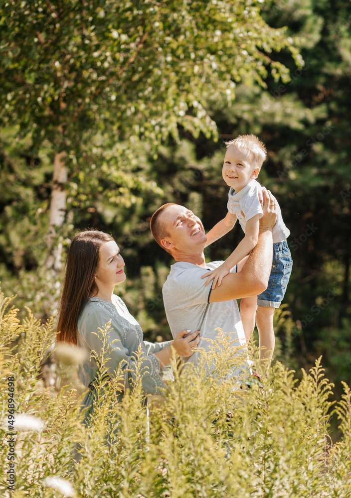 Fototapeta premium Happy young family of three spend time together and smiling while standing in nature.