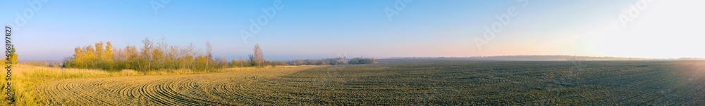 Panorama of plowed field on a background of the sun