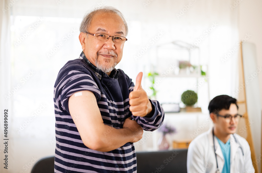 Safe vaccination for old people. Elder man in medical getting flu or Covid-19 vaccine sitting on sofa at home. Asian Doctor or nurse giving flu or Covid-19 shot to senior. Safe vaccination for old people. Elder man in medical getting flu or Covid-19 vaccine sitting on sofa at home. Asian Doctor or nurse giving flu or Covid-19 shot to senior.