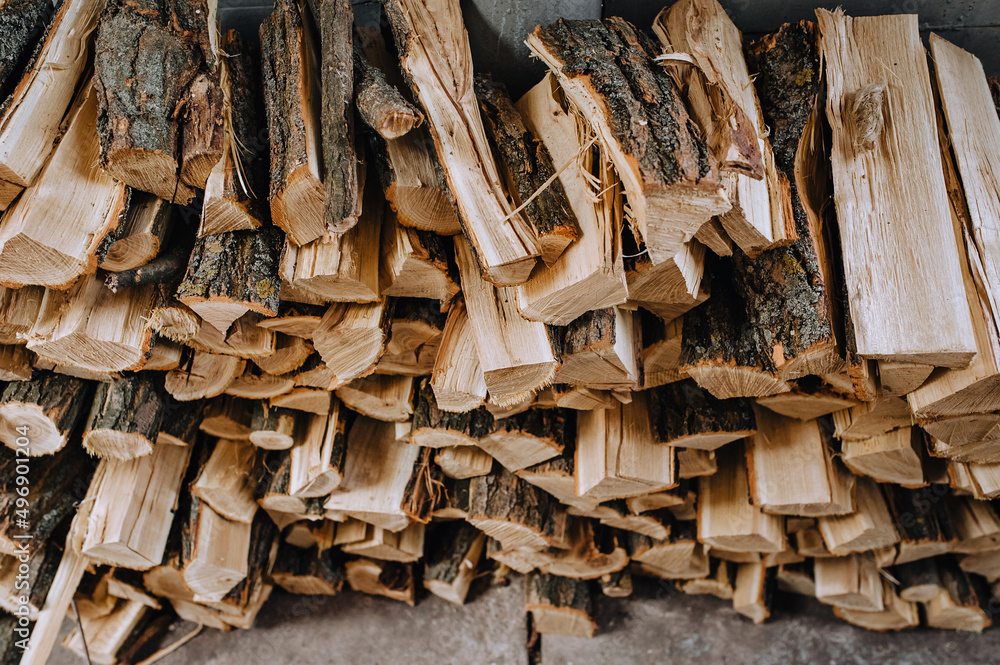 A lot of logs chopped with an ax, dry acacia firewood, fir trees for heating are stacked in a row close-up. A lot of logs chopped with an ax, dry acacia firewood, fir trees for heating are stacked in a row close-up.