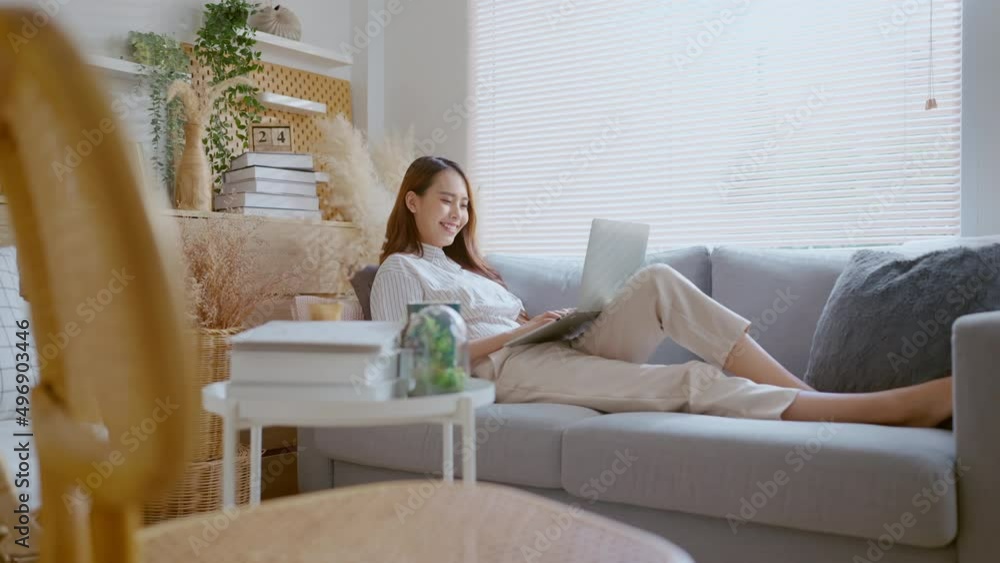 young attractive asian female working at home hand use laptop checking search schedule working process planning report with leisure relax on sofa in living room with morning light peaceful moment young attractive asian female working at home hand use laptop checking search schedule working process planning report with leisure relax on sofa in living room with morning light peaceful moment