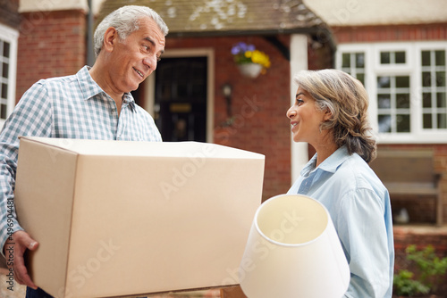 Mature Couple Carrying Boxes On Moving Day In Front Of Dream Home photo