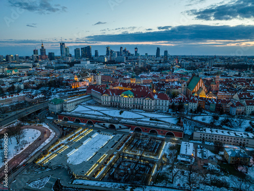 Widok na zamek królewki i stare miasto w Warszawie z drona, w tle wieżowce, zaśnieżone dachy, zachód słońca