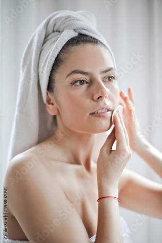 young woman cleans her face with a cleanser