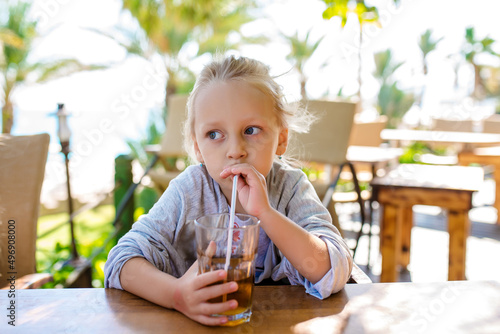 Fun cute kid girl drinking healthy smoothie juice in street restaurant. Closeup toned portrait