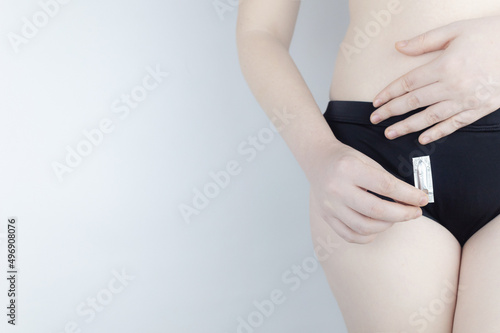 Vaginal or rectal candle in the hands of a woman against the background of the abdomen and underwear. Treatment vaginal infections, candidiasis, thrush and sexually transmitted infections