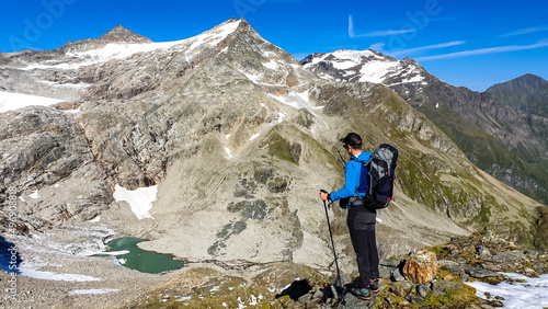 Hiking man with scenic view on Hoher Sonnblick in High Tauern mountains in Carinthia, Salzburg, Austria, Europe, Alps. Glacier lakes of Goldbergkees in Hohe Tauern National Park. Patagonia landscape photo