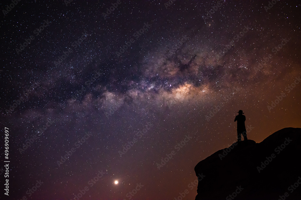 Landscape with the Milky Way in the night sky with stars and the shadow of a man standing happily looking at the mountain sky. beautiful universe space background