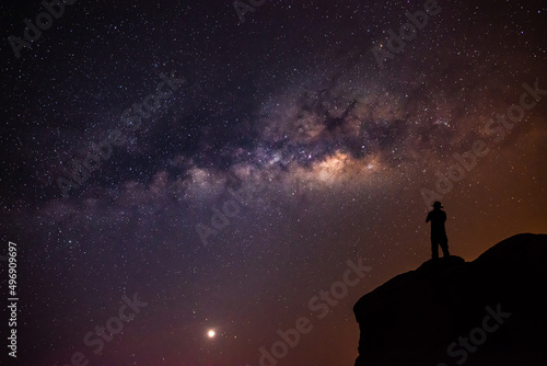 Landscape with the Milky Way in the night sky with stars and the shadow of a man standing happily looking at the mountain sky. beautiful universe space background