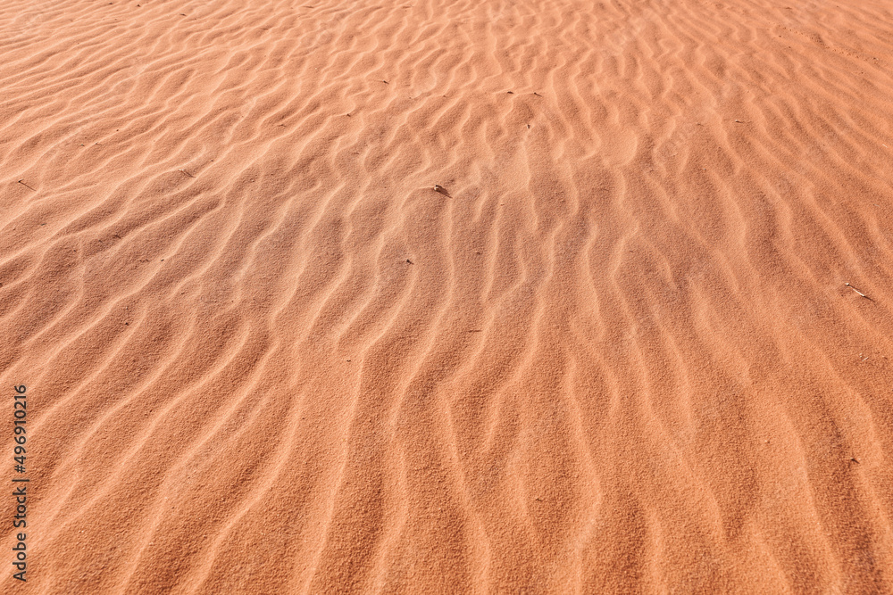 Sun shines to red desert sand, wind formed small ridges, closeup detail Sun shines to red desert sand, wind formed small ridges, closeup detail