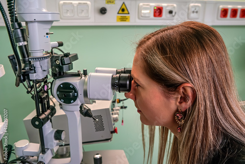 Fototapeta Naklejka Na Ścianę i Meble -  Young woman looking into eye examination machine in optometrist ambulance