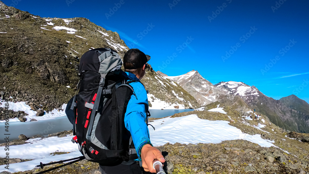 Hiking man with scenic view on Hoher Sonnblick in High Tauern mountains in Carinthia, Salzburg, Austria, Europe, Alps. Glacier lakes of Goldbergkees in Hohe Tauern National Park. Patagonia landscape