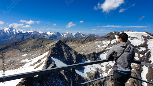 Man enjoying the panoramic view from Hoher Sonnblick on mountain ranges of High Tauern Alps in Carinthia, Salzburg, Austria, Europe. Goldberg group in Hohe Tauern National Park. View on Grossglockner